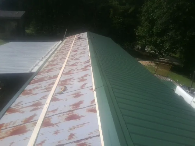 Old rusted panels beside newly installed green metal roofing — Wind Damage Roof Repair by Roofing Brothers in Lyman